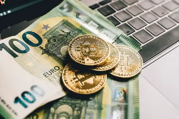 Euro notes and a laptop showing a trading chart on a desk