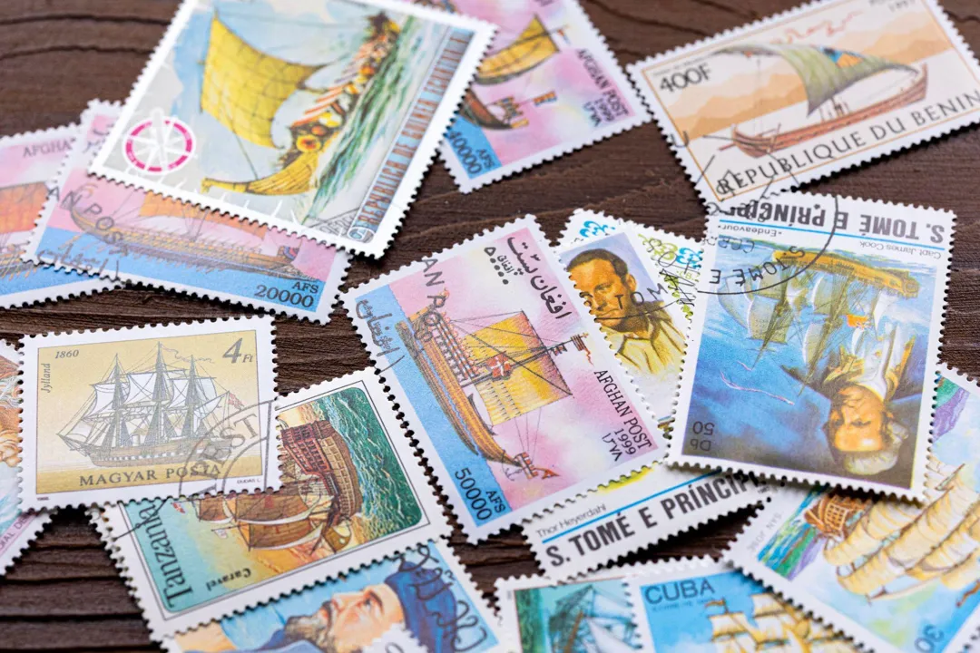 Postage stamps from São Tomé and Príncipe and other countries spread on a wooden table
